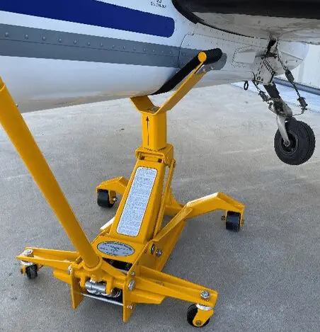 A yellow jack stands on the ground near an airplane.